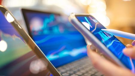 Two laptops and phone showing various graphs