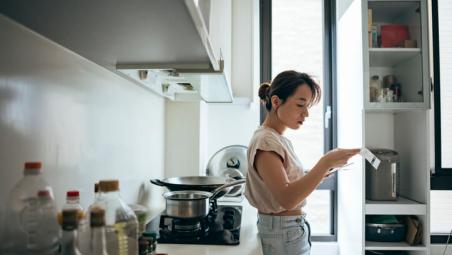 woman leaning against counter in kitchen reading mail
