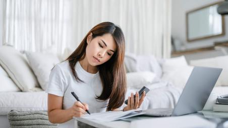 woman sitting on the floor by the sofa working on finances