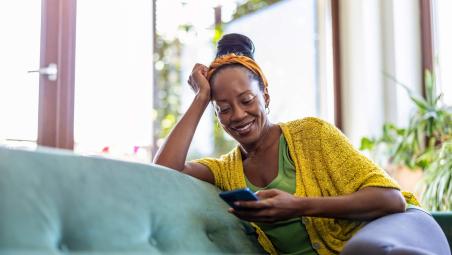 woman using her smartphone relaxing on the sofa