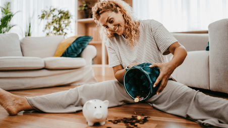 Woman sat on floor emptying piggy bank of coins