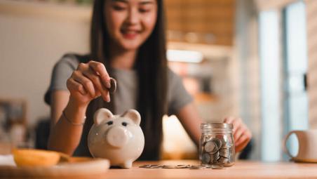 young woman putting coins in piggy bank